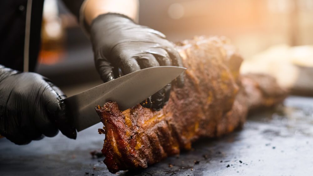 A man slicing ribs at a BBQ restaurant in Fredericksburg, TX.